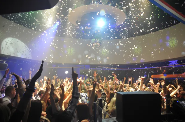 A crowd beneath colourful lights at a live music event
