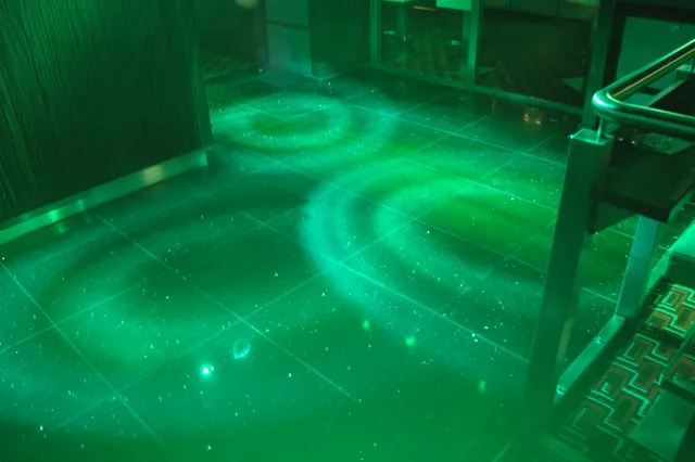 Green light projected in circles across a dark surface